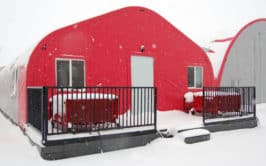 A red building with snow-covered railings and steps