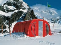 A bright red tent set up in a snowy mountain area