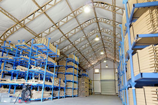 The inside of a tall fabric warehouse filled with blue shelving and stacked boxes