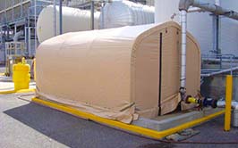 A small beige fabric structure next to industrial equipment