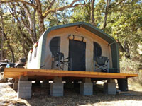 A cabin tent on a wooden platform in the woods
