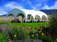 Golf carts are parked under a large white tent with colorful flowers in front