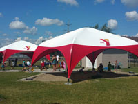 Kids playing under large red and white plastic tents at a park