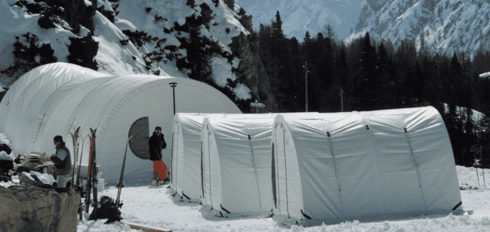 two white fabric quonset huts in snow