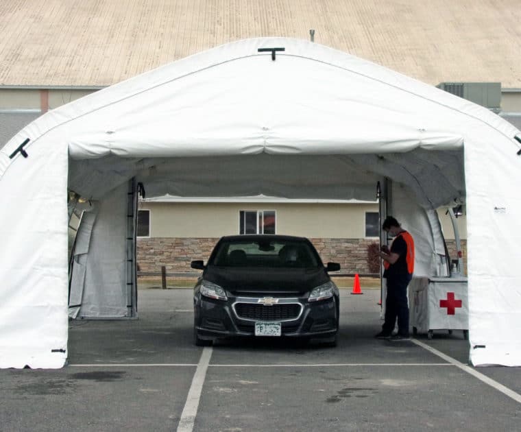 A black chevy parked inside of a vaccine and testing drive through structure