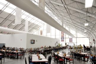 Another interior view of the Mesa State College dining hall and bookstore highlights optional HVAC ducts and our skylight material near the peak, enhancing comfort and natural light within the pre-engineered fabric building from Alaska Structures®.