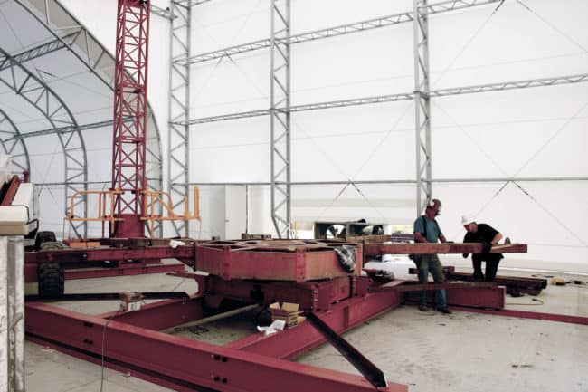 Alaska Structures DAGB fabric building for industrial workshop The interior of an industrial workshop, housed in a DAGB Series™ fabric building from Alaska Structures®, provides an organized space for repairing and refitting large equipment.