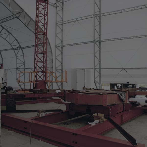 The interior of an industrial workshop, housed in a DAGB Series™ fabric building from Alaska Structures®, provides an organized space for repairing and refitting large equipment.