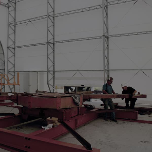 The interior of an industrial workshop, housed in a DAGB Series™ fabric building from Alaska Structures®, provides an organized space for repairing and refitting large equipment.