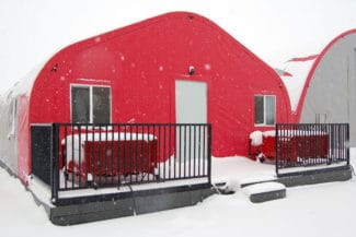 A red tent cabin covered in snow