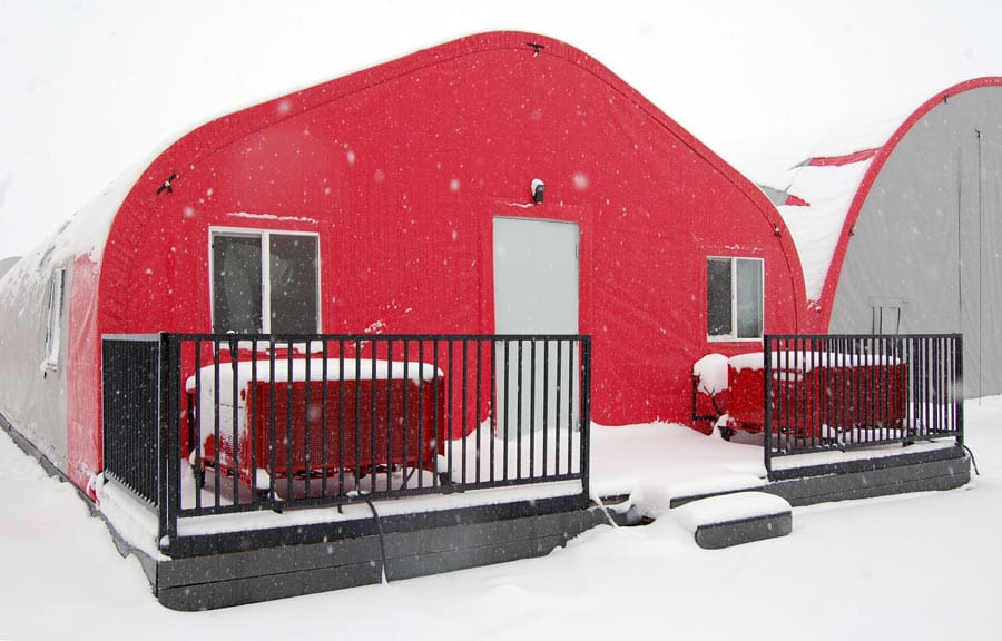 A red tent cabin covered in snow