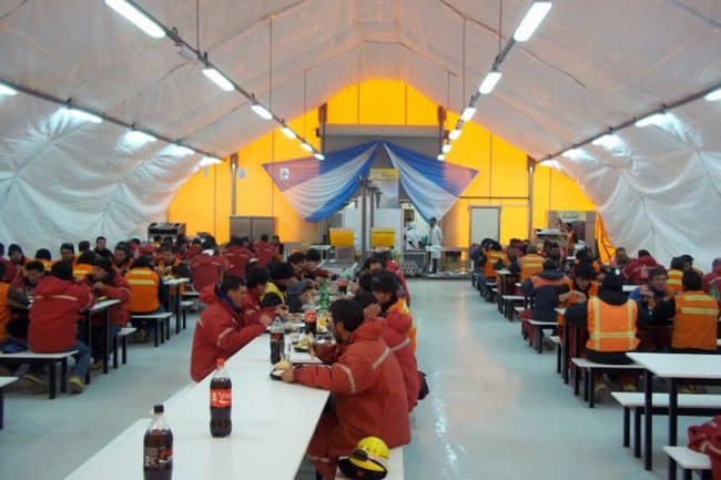 alaska-structures-dining-facility-for-mining-camp-interior-1 The interior of a dining hall at a remote mining camp in South America features a DAGB Series™ fabric building from Alaska Structures®, seamlessly connected to kitchen containers for efficient meal preparation and dining.
