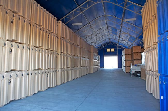 alaska-structures-industrial-warehouse-and-storage-building-18 The interior of a fully enclosed DAGB Series™ industrial warehouse from Alaska Structures® is used to store wood crates and reusable shipping containers, providing secure and organized storage.
