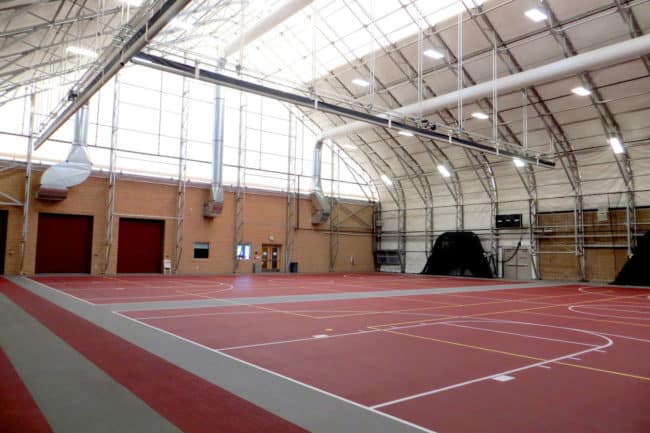 The interior of a large indoor training facility, built using a pre-engineered building from Alaska Structures®, features skylights, lighting, electrical, and HVAC systems, providing a well-equipped and comfortable space for training activities.