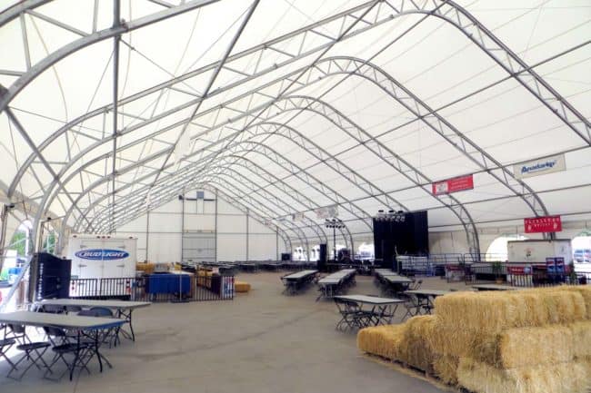 Alaska Structures large outdoor dining facility interior The roll-up side curtains of the Colorado State Fair event pavilion, a DAGB Series™ fabric building from Alaska Structures®, offer ventilation and create an open-air atmosphere for enhanced event experiences.