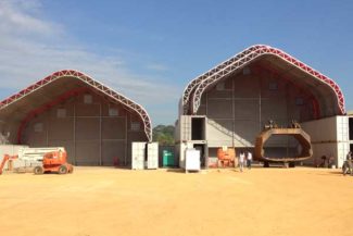 Two large industrial tents with equipment and people outside