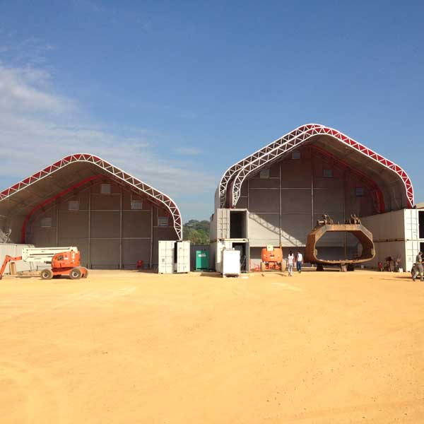 Two large industrial tents with equipment and people outside