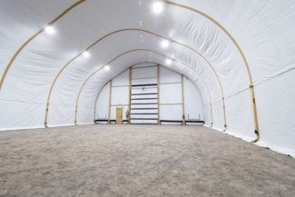 The inside of a large, empty white tent with bright lights