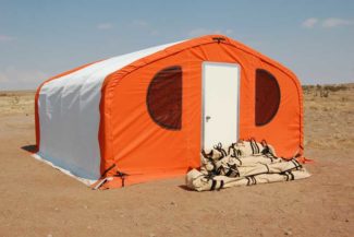 An orange and white tent with gear bags piled outside