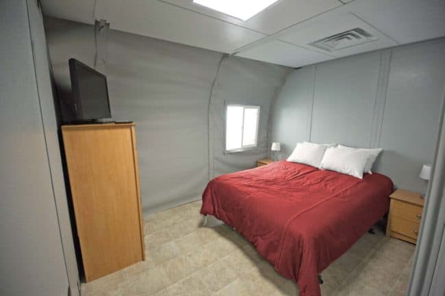 Alaska Structures homeless shelter and navigation center Denali series fabric building The interior of an HGB Series™ fabric building from Alaska Structures® features customer-installed hard walls and a drop ceiling, demonstrating the building's versatility and customizable design.