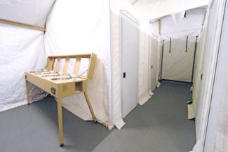 The interior of a tent with sinks and partitioned areas