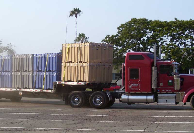 A red truck carrying a load of large metal boxes