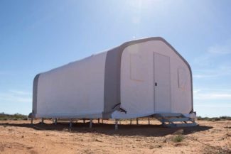 A white fabric building cabin set up in a sunny desert area