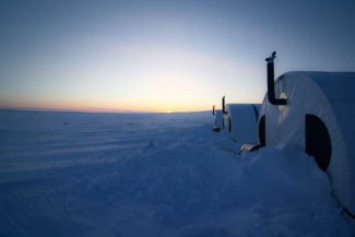 Tents set up in a snowy landscape during sunset