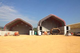 Two large industrial tents with equipment and people outside