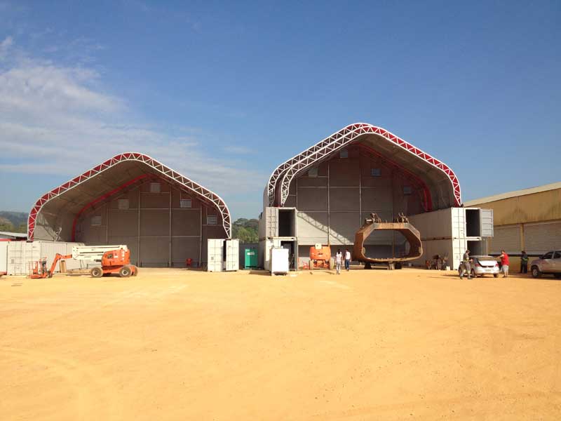 Two large industrial tents with equipment and people outside