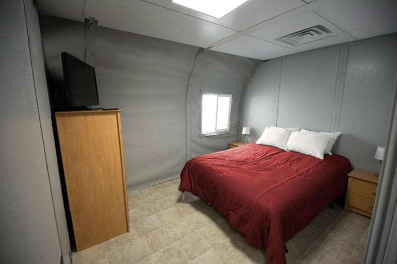 A bedroom inside a fabric tent with a red bedspread