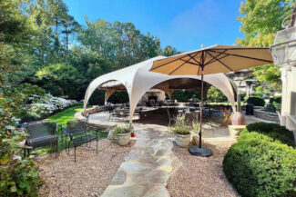 A WeatherPort® Octopae™ canopy structure from Alaska Structures® provides an elegant, covered outdoor dining area for guests to enjoy the scenic gardens at Portico Restaurant & Bar in Richmond, Virginia.
