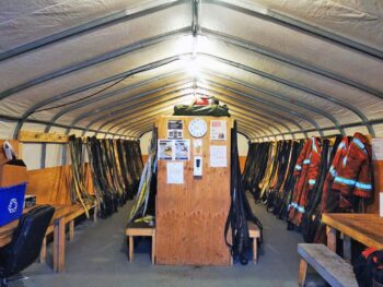 Interior of a mine dry and locker room with hanging cold-weather gear at a northern Canada exploration camp