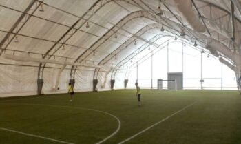 Open-span interior of a 70 x 130 ft indoor sports and recreation building at a West African mining camp